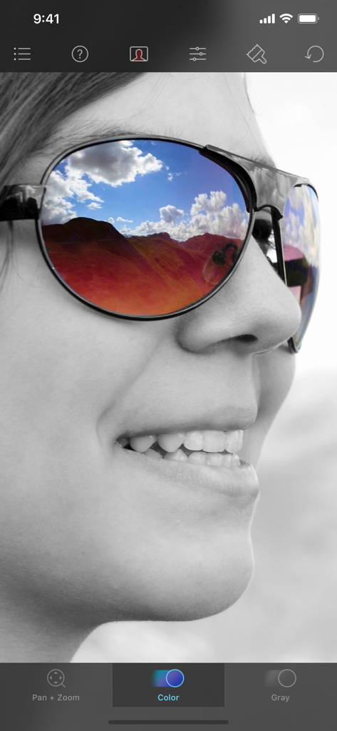 Color Splash - Una foto en blanco y negro de una mujer con un reflejo vibrante de paisaje a color en sus gafas de sol siendo editada en la aplicación Color Splash.