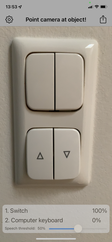 The AI-Camera app interface showing a 100 percent confidence detection of a light switch on a wall.
