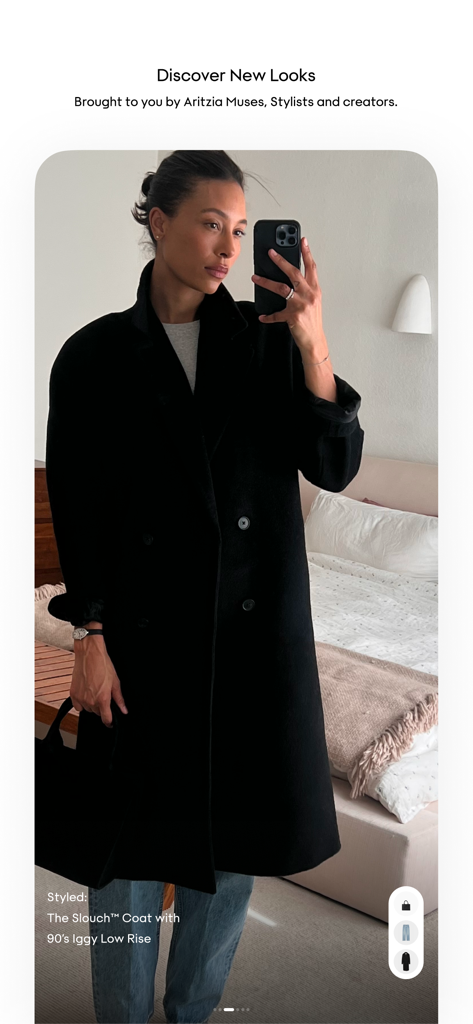 Aritzia - Una mujer usando un abrigo largo negro y jeans en una selfie de espejo en el Feed de Estilo de la app Aritzia