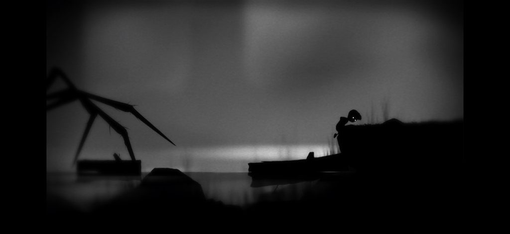 Playdead's LIMBO - Un niño silueteado se enfrenta a las patas de una araña gigante en un bosque oscuro y brumoso del juego LIMBO.