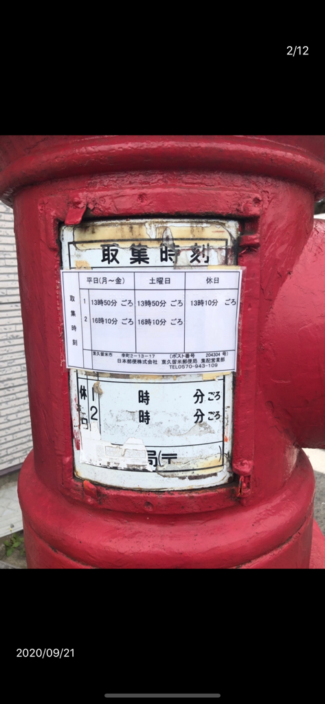 A close up of a red mailbox in Japan displaying its mail collection schedule