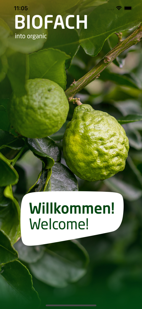 BIOFACH 2025 - Schermata di benvenuto dell'app BIOFACH 2025 con agrumi biologici verdi e un messaggio di benvenuto in tedesco e inglese