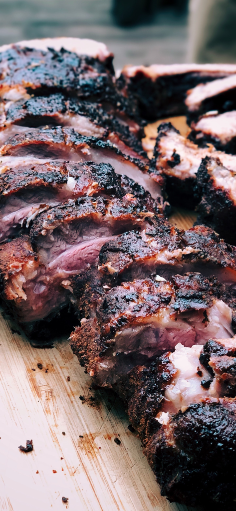 BBQ Guru - Slices of perfectly smoked BBQ meat on a wooden cutting board.