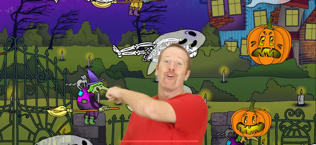 Steve gesturing in front of a Halloween themed background with pumpkins and animated witches