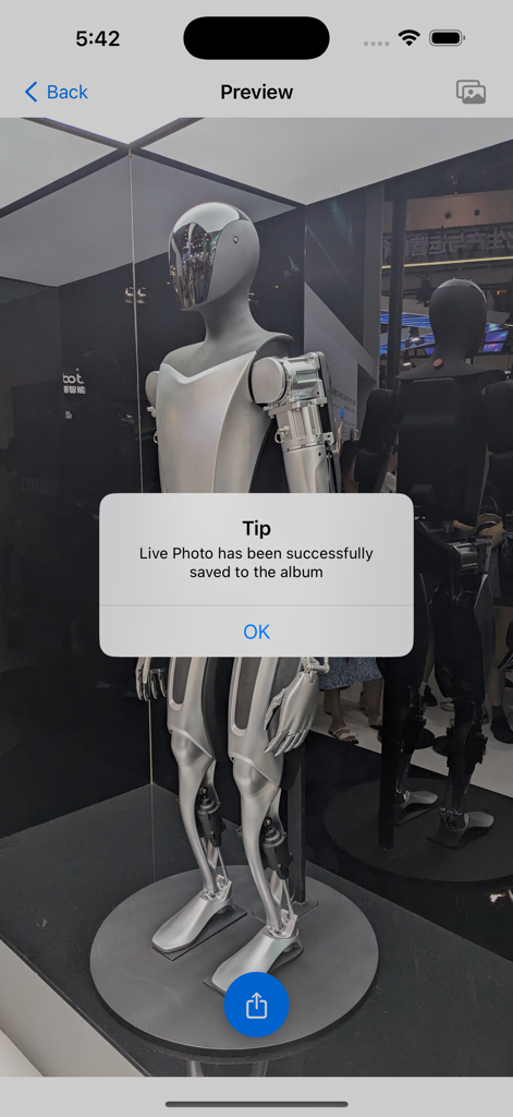 A screenshot of the Motion2Live app showing a success notification that a Live Photo has been saved to the album over a photo of a robot