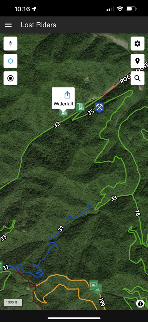 Satellite map view of off-road trails with a waterfall marker in the Lost Riders navigation app.