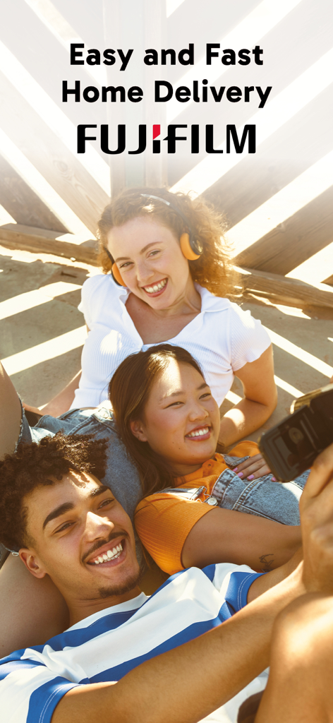 Un groupe d'amis souriants prenant un selfie avec un texte faisant la promotion de la livraison rapide à domicile de tirages photo Fujifilm.