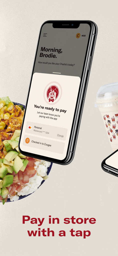 A smartphone showing the Chargrill Charlie's app interface for paying in-store with a tap alongside a fresh salad and milkshake.