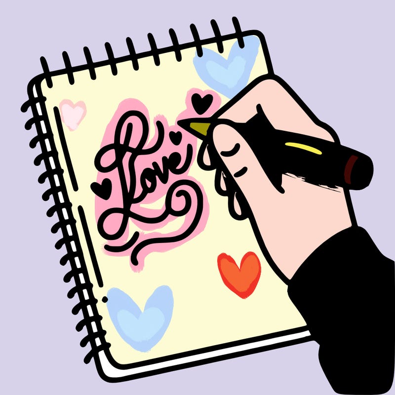 a hand writing “love” in calligraphy on a notebook