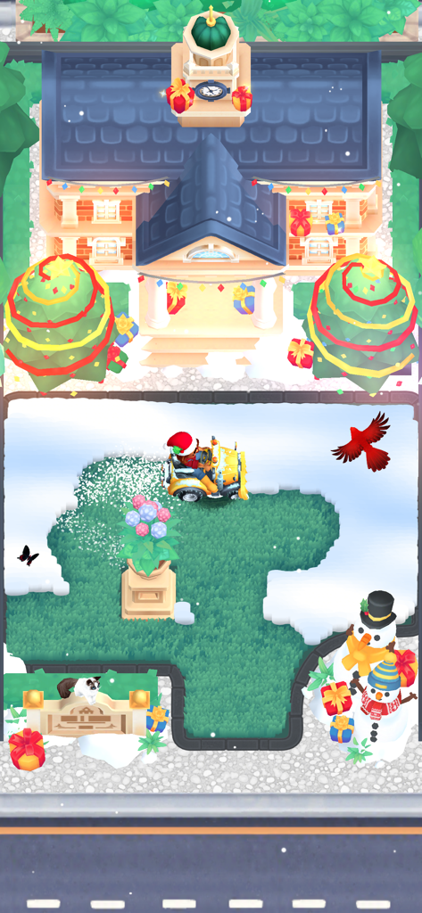 It's Literally Just Mowing - 黄色い芝刈り機が、クリスマスツリーと雪だるまで飾られた庭の雪を片付けている。