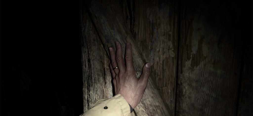 Una vista cercana en primera persona de una mano apoyada en una superficie de madera oscura en Resident Evil Village
