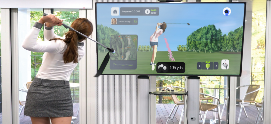 SmartGolf AI Analyzer - A woman practicing her golf swing with the SmartGolf AI Analyzer and a 3D avatar simulator on a large screen