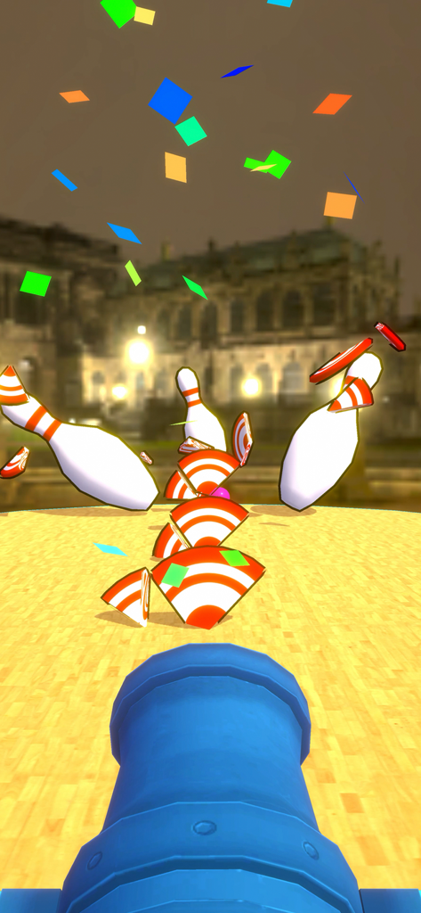 Eine blaue Kanone feuert einen Bowlingball ab und zerstört Pins und Ziele mit buntem Konfetti im Hintergrund.