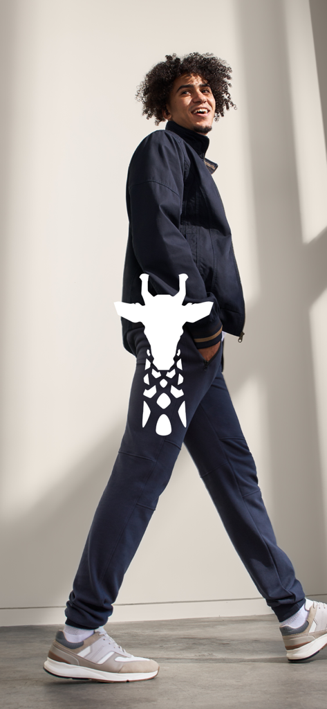 American Tall - A smiling tall man wearing a navy jacket and joggers with the American Tall giraffe logo