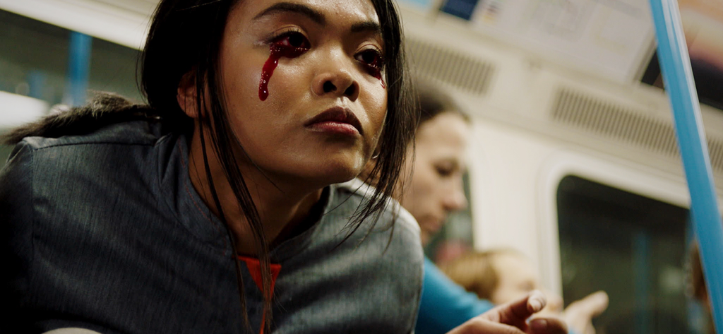 Una mujer con sangre chorreando de sus ojos en un tren en una escena de la película interactiva The Complex