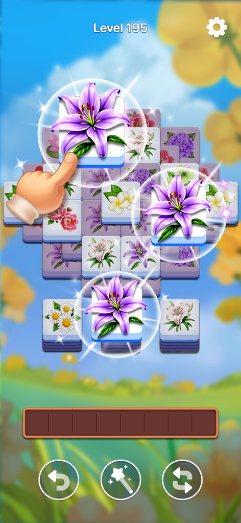 A hand selecting a purple lily tile to match three in the Bloom Tile floral puzzle game.