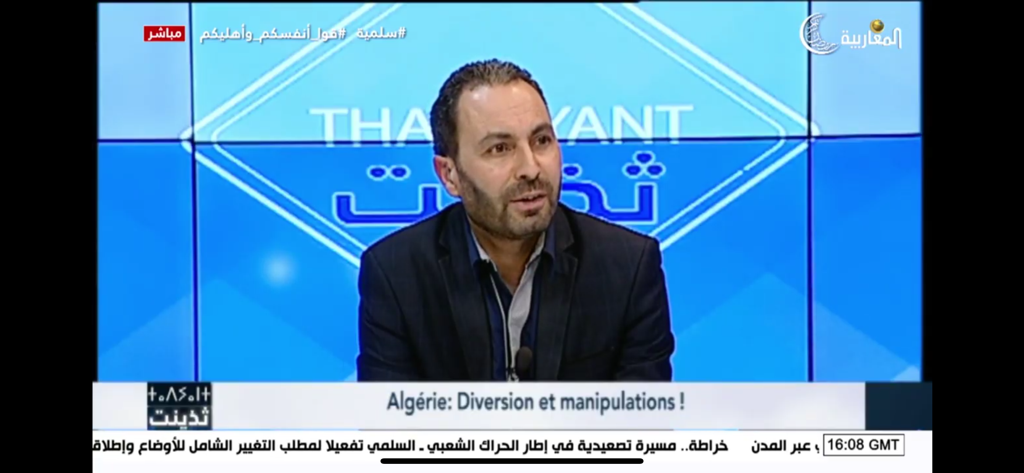 Un presentador de noticias en Almagharibia TV discutiendo un tema sobre Argelia en un estudio.