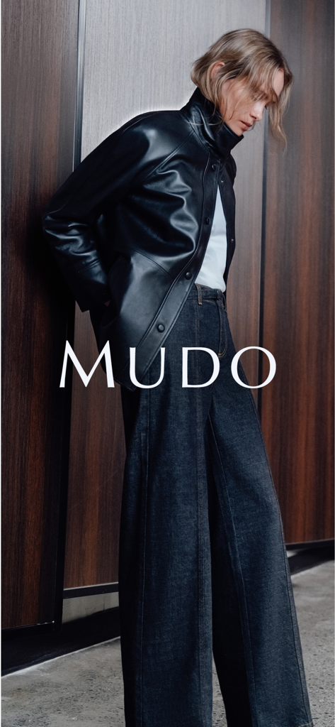 Mudo - Eine Frau trägt eine stilvolle schwarze Lederjacke und eine dunkle Wide-Leg-Jeans mit dem Mudo-Logo-Overlay