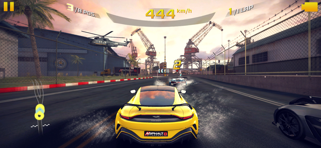 A yellow sports car racing at 444 km per hour on a harbor track with cranes and a helicopter in the background
