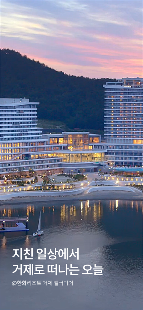 夕暮れ時、海に浮かぶ帆船を眺める豪華なモダンリゾートの建物。