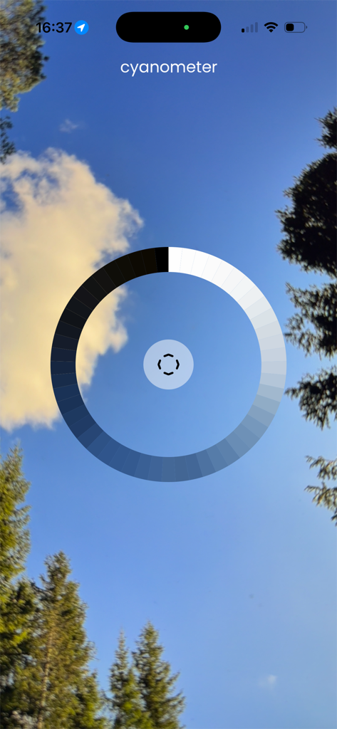 Cyanometer - Cyanometerアプリのインターフェース。円形の青いカラースケールが澄んだ空のビューに重ねられています。