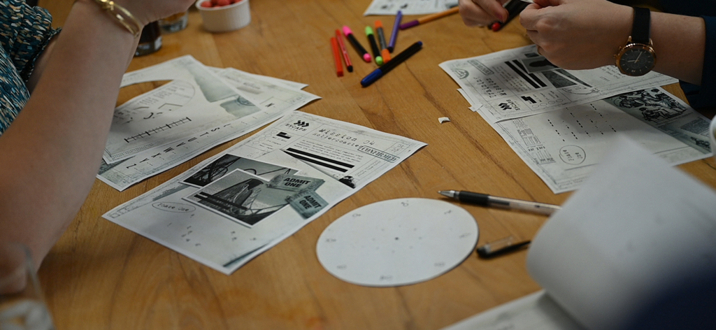 Escape Team MDM - A group of people collaborating at a wooden table using printed mission sheets and puzzles from the Escape Team MDM game