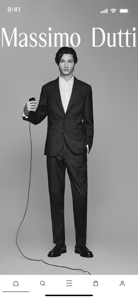 Un modello maschile che indossa un abito scuro sartoriale in un editoriale minimalista per l'app Massimo Dutti