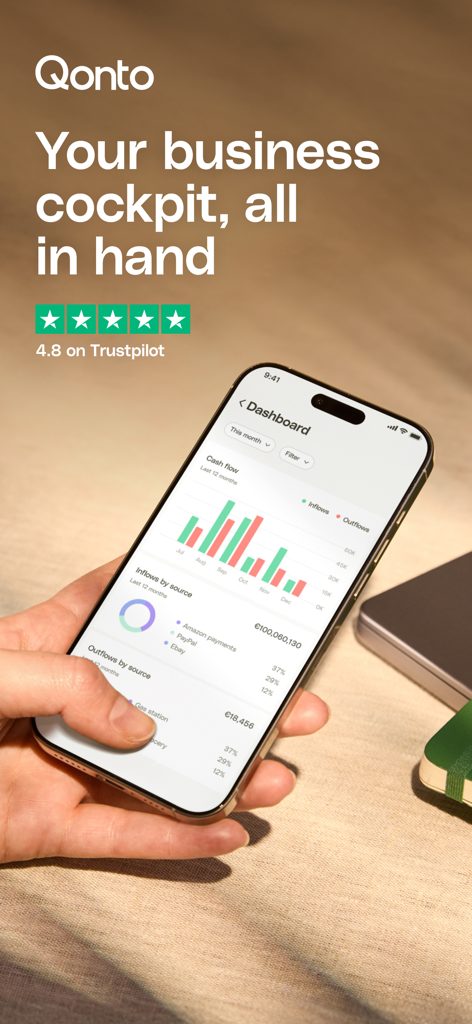 Qonto - Business Finance App - A hand holding a smartphone showing the Qonto business finance dashboard with cash flow charts and analytics