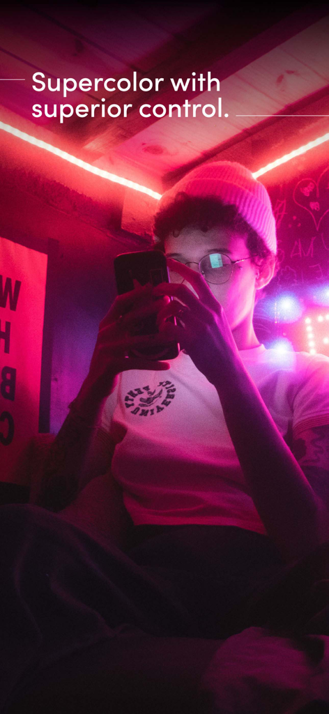 Una persona usando un smartphone para controlar iluminación LED inteligente de colores en una habitación.