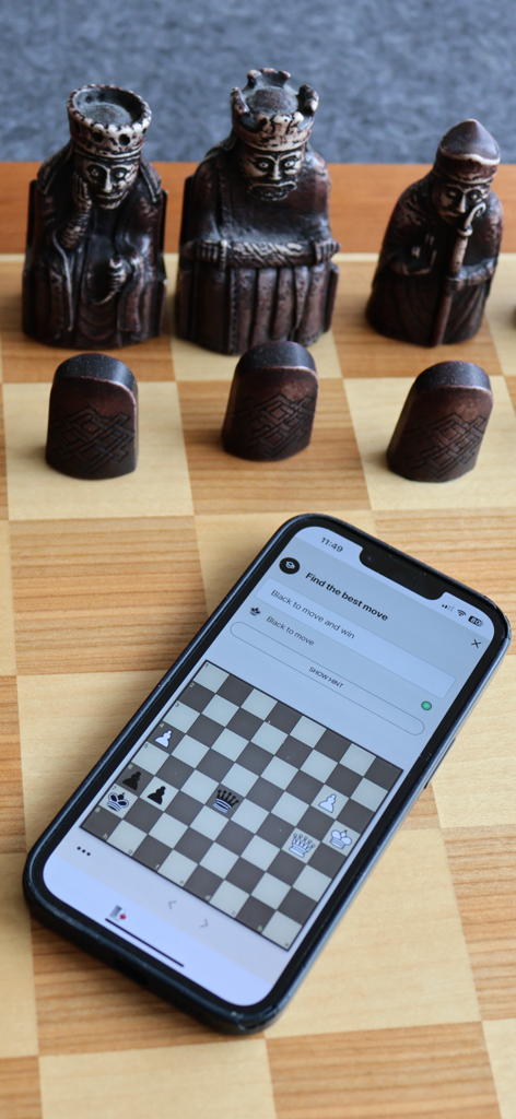 Chessconnect - iPhone displaying a chess puzzle from the Chessconnect app on a physical wooden chessboard