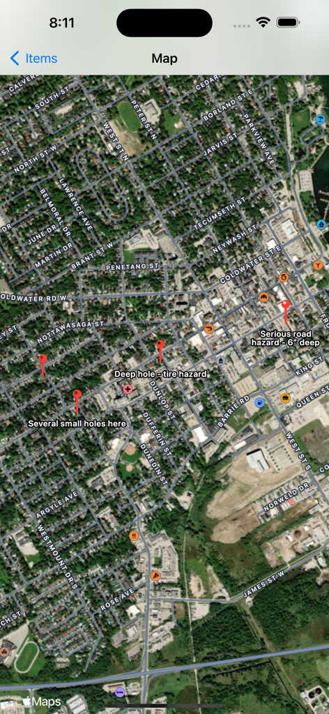 GeoLog - Satellite map view in the GeoLog app showing custom red pins and labels for road hazards such as deep holes and tire hazards.