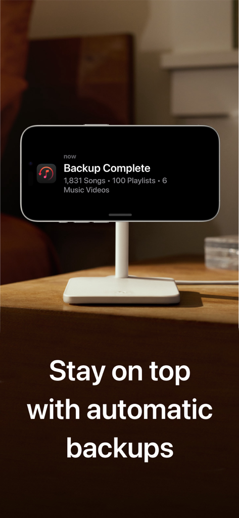 Hezel for Apple Music - iPhone on a charging stand displaying a Hezel app notification for a completed automatic music library backup.