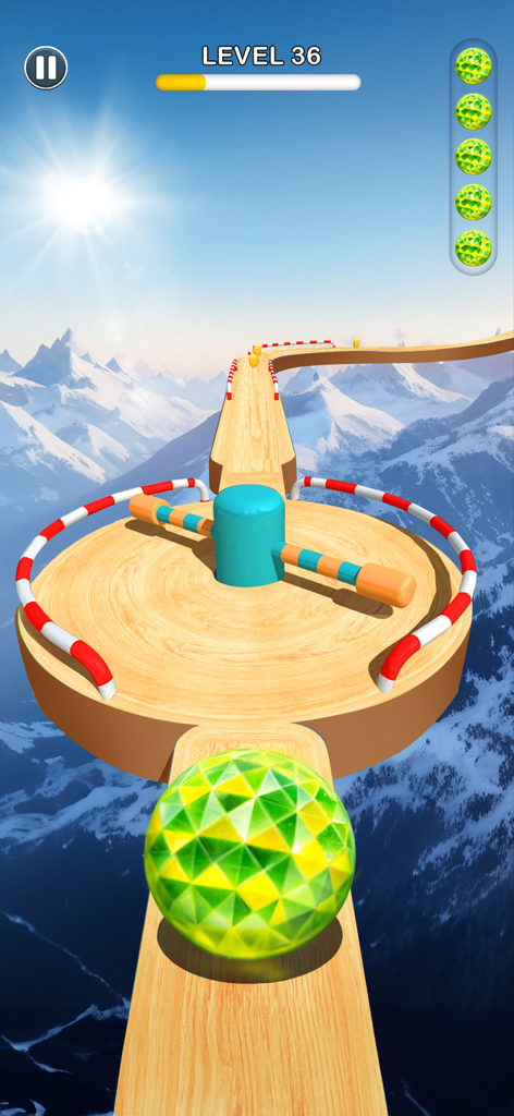 A patterned green ball on a wooden track high above snowy mountains facing a rotating hammer obstacle