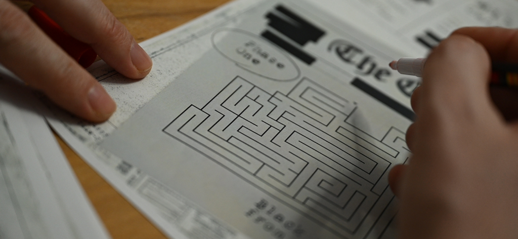 Escape Team MDM - A person solving a printed paper maze puzzle with a red marker