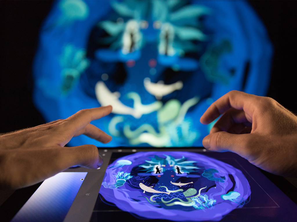 Manos creando arte digital en vivo en un iPad usando Tagtool con el visual proyectado en una pared