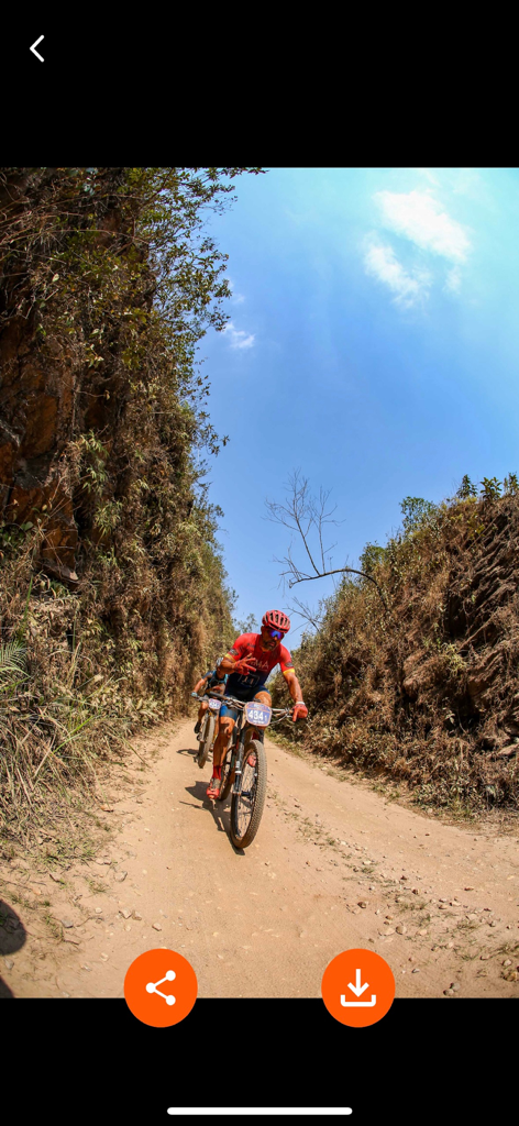 Professional action photo of a cyclist on a dirt trail inside the Fotop mobile app interface.