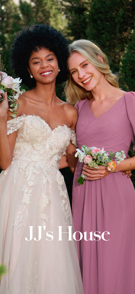 Una novia con un vestido de encaje y una dama de honor con un vestido malva sonriendo juntas.