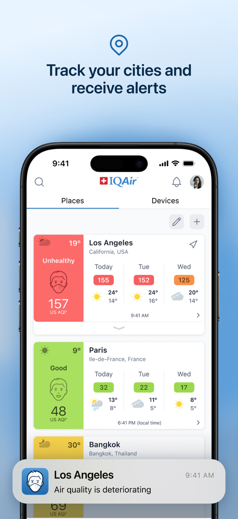 A smartphone showing the IQAir app interface with air quality levels for Los Angeles and Paris plus a real-time deterioration alert