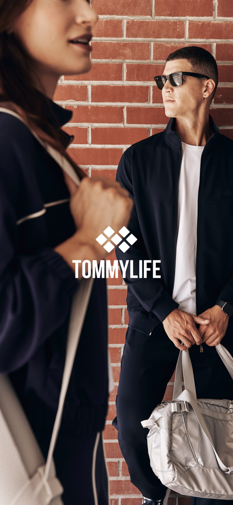 Homme et femme portant des vêtements de sport tendance TommyLife devant un mur de briques