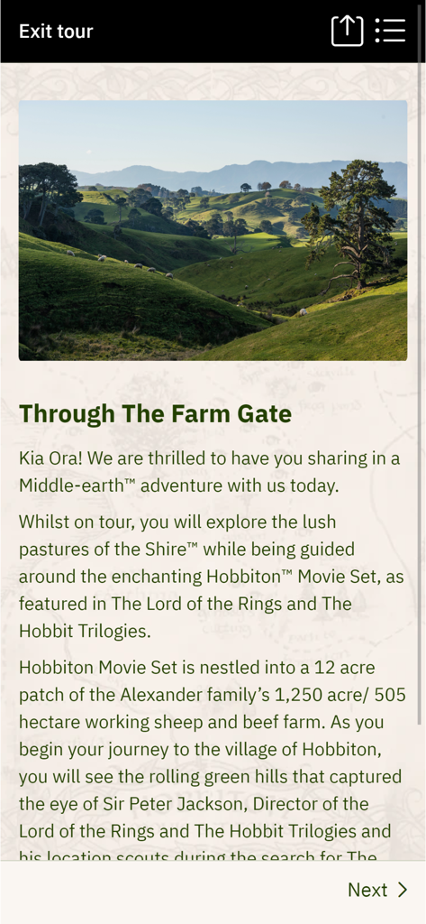 Pantalla de bienvenida de la aplicación compañera del tour de Hobbiton que muestra las colinas verdes ondulantes de La Comarca y texto introductorio del tour.