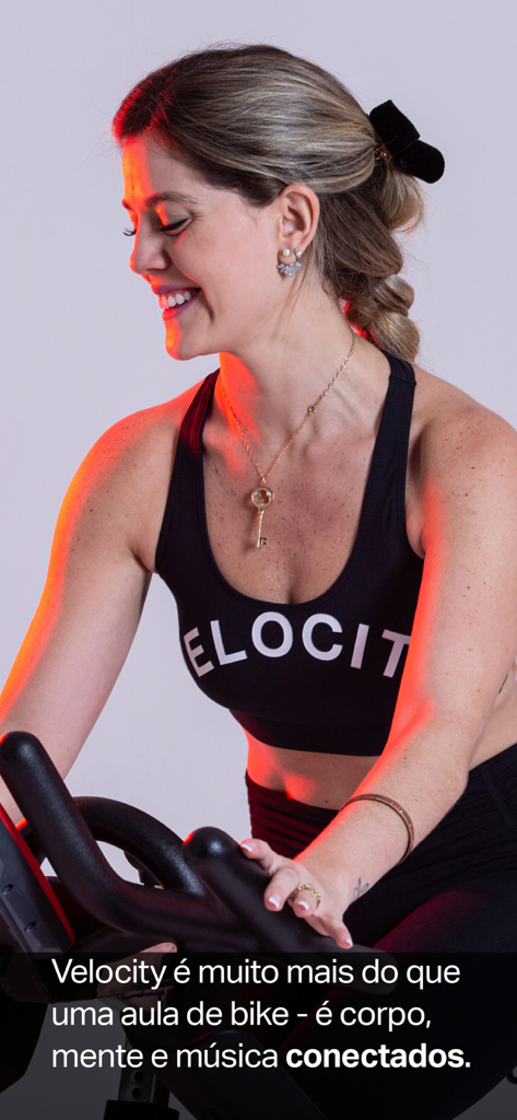 Una mujer sonriente montando una bicicleta estática de interior en Studio Velocity