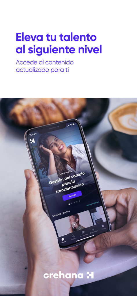 Persona sosteniendo un smartphone que muestra la aplicación Crehana Learn con un curso de desarrollo profesional en la pantalla.