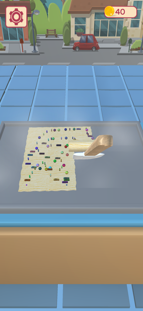 Una espátula enrollando una fina capa de helado con toppings coloridos en el juego Ice Cream Rolls ASMR Maker.