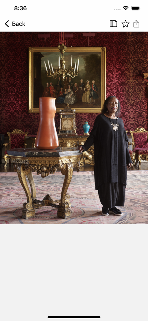 Architectural Digest - A woman standing in an ornate room with red damask wallpaper and classic decor