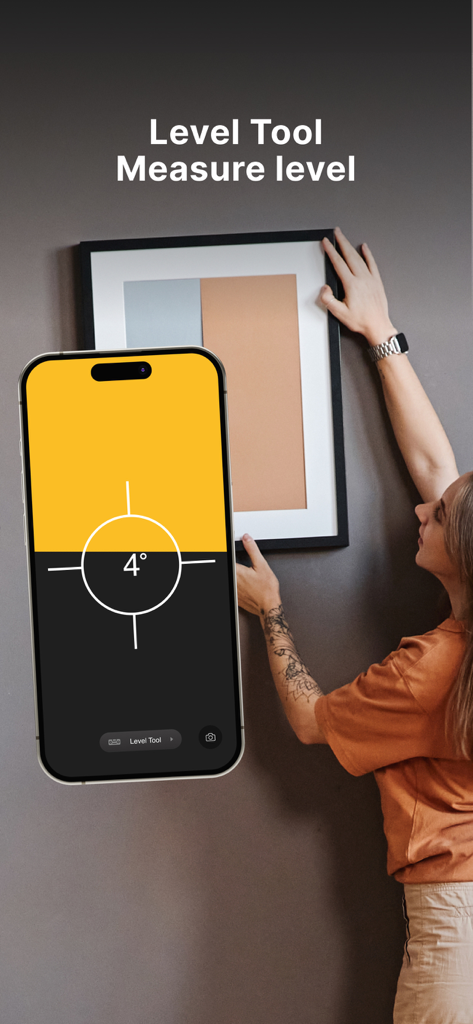 Measuring Tape: Digital Ruler - A person using the digital level tool on an iPhone to hang a picture frame straight on a wall