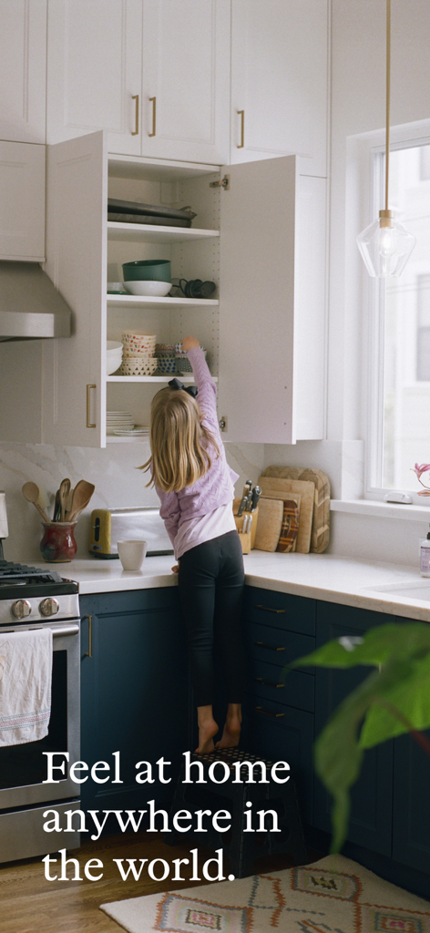 A young girl reaching into a kitchen cupboard in a lived-in home with the text Feel at home anywhere in the world.