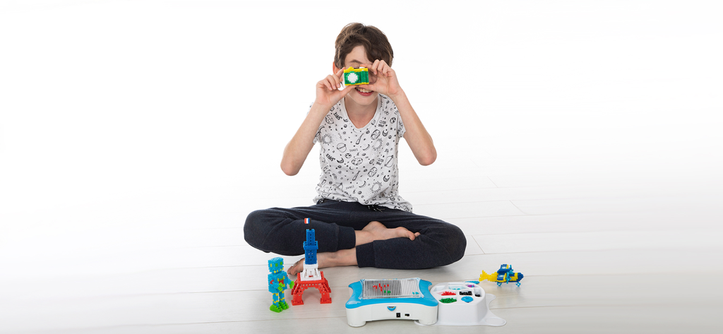 A child playing with smART pixelator 3D creations including a robot and Eiffel Tower