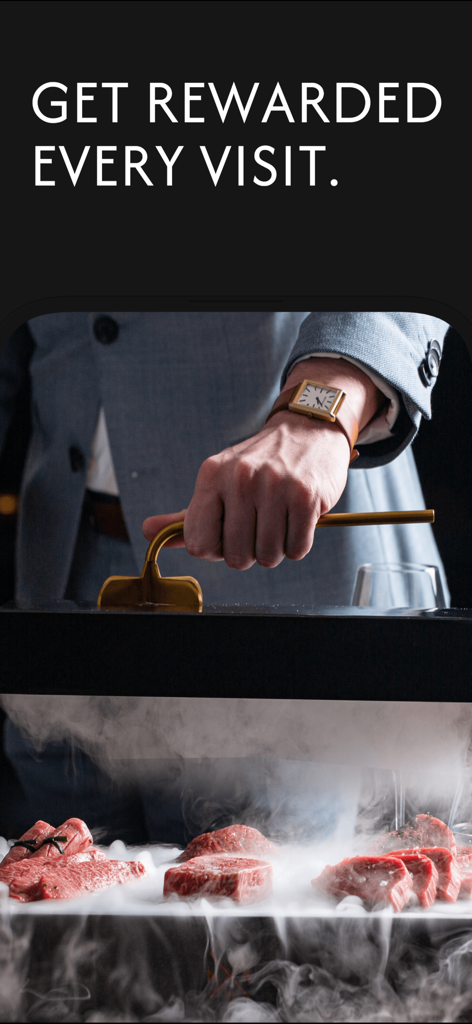A professional chef in a suit presenting premium steaks with a dry ice mist effect in a high-end restaurant setting.