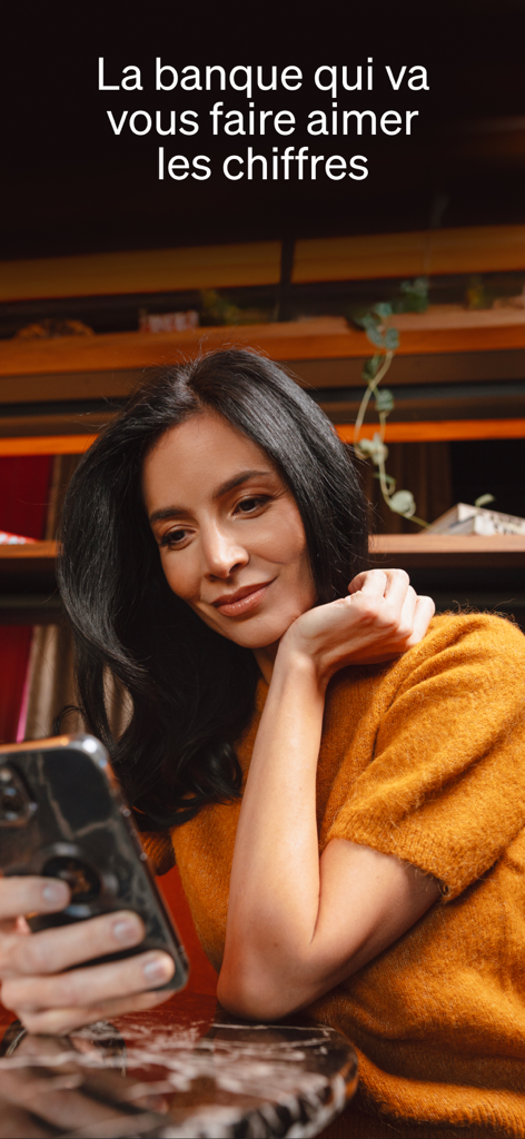 Una mujer sonriendo mientras usa la aplicación de banca móvil Fortuneo en su smartphone