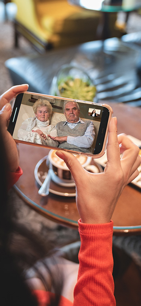 ONSCREEN Family - Senior Care - A caregiver uses a smartphone for a video call with an elderly couple via the ONSCREEN app